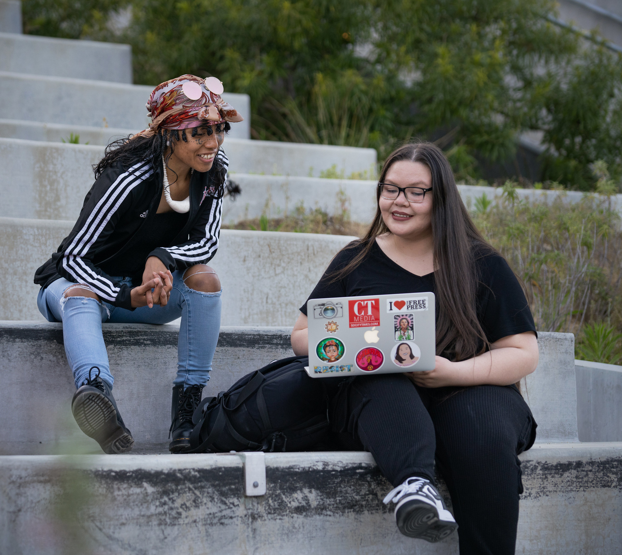 A student is working on a laptop and other student is looking over her shoulder.