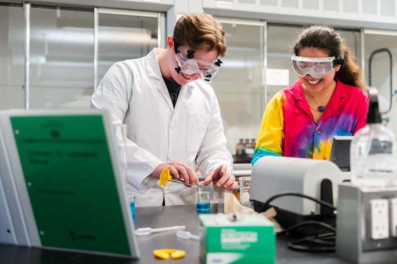Two students wearing googles in a science lab