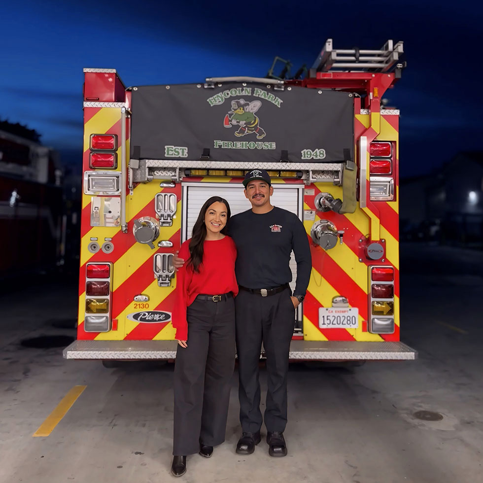 Ulizes Sanchez stands with a woman at the back of a fire truck