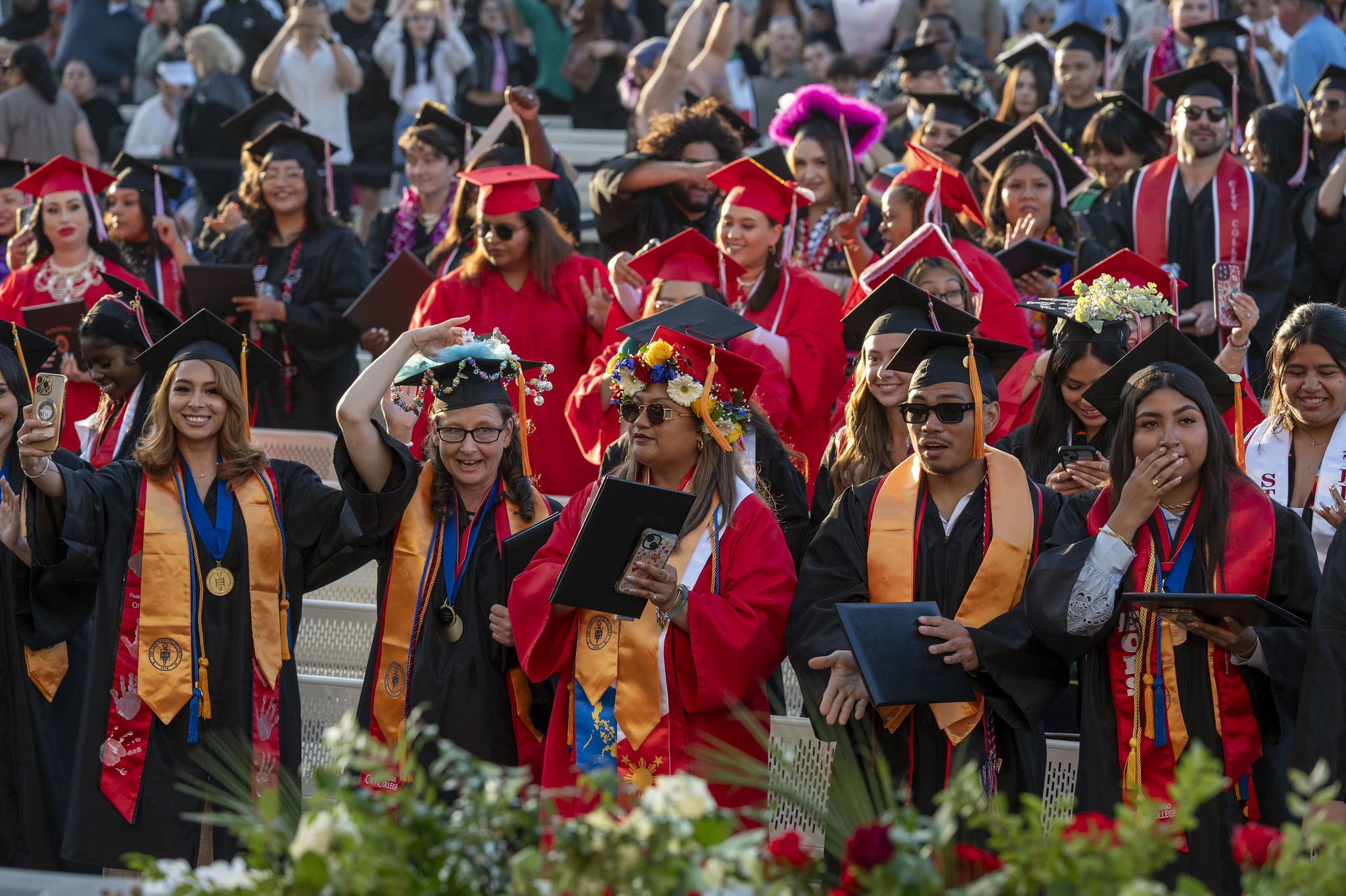 
All of the graduates in the audience stand to turn their tassels.

