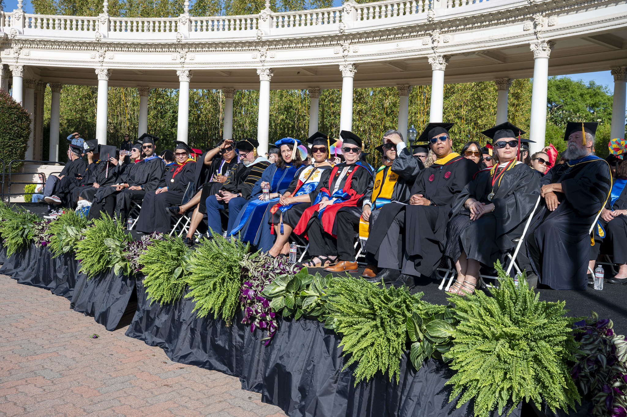 
City College leadership in caps and gowns on the stage at commencement.
