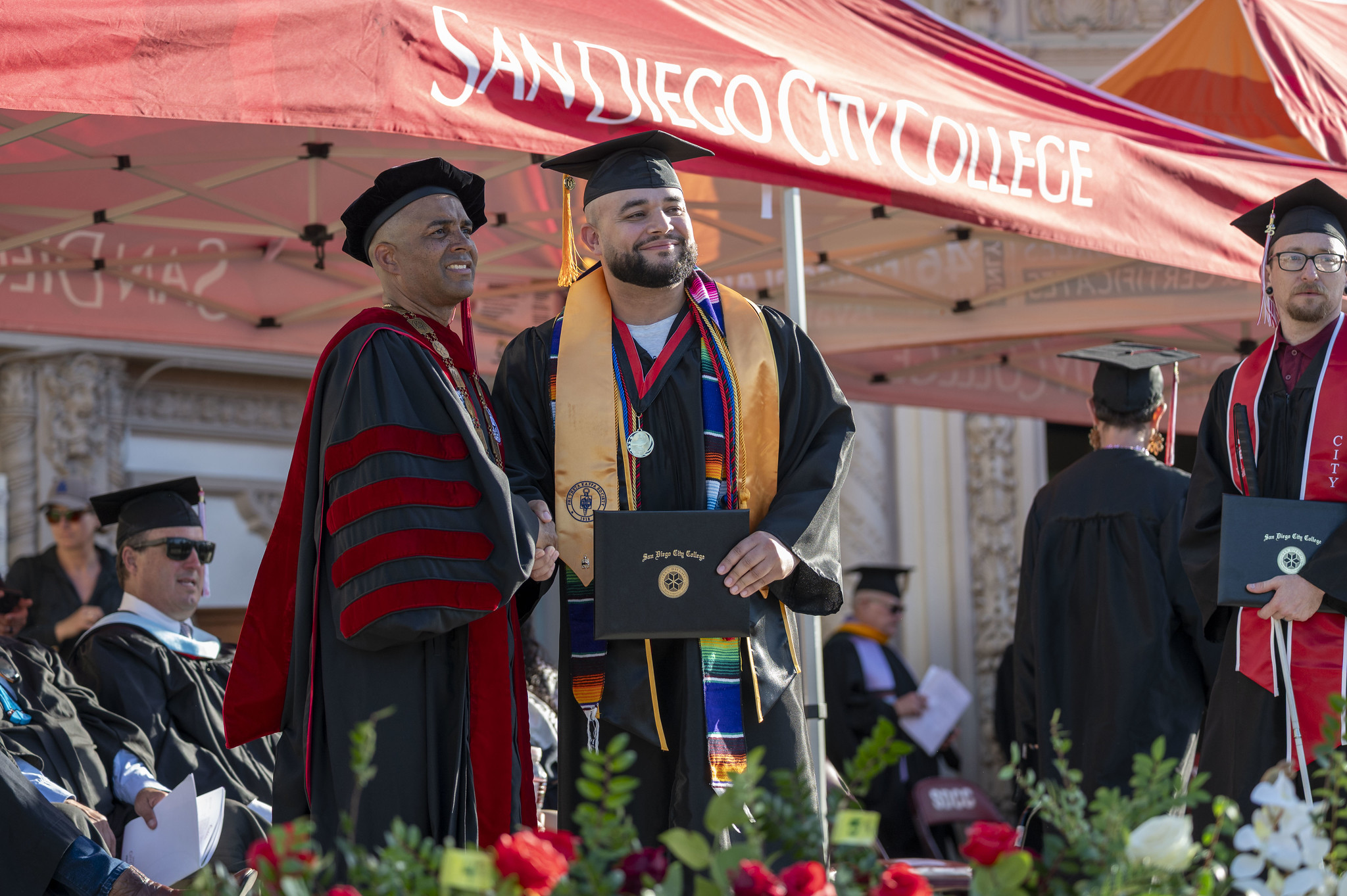 
City College President Ricky Shabazz shakes the hand of an honors student as he receives his degree.
