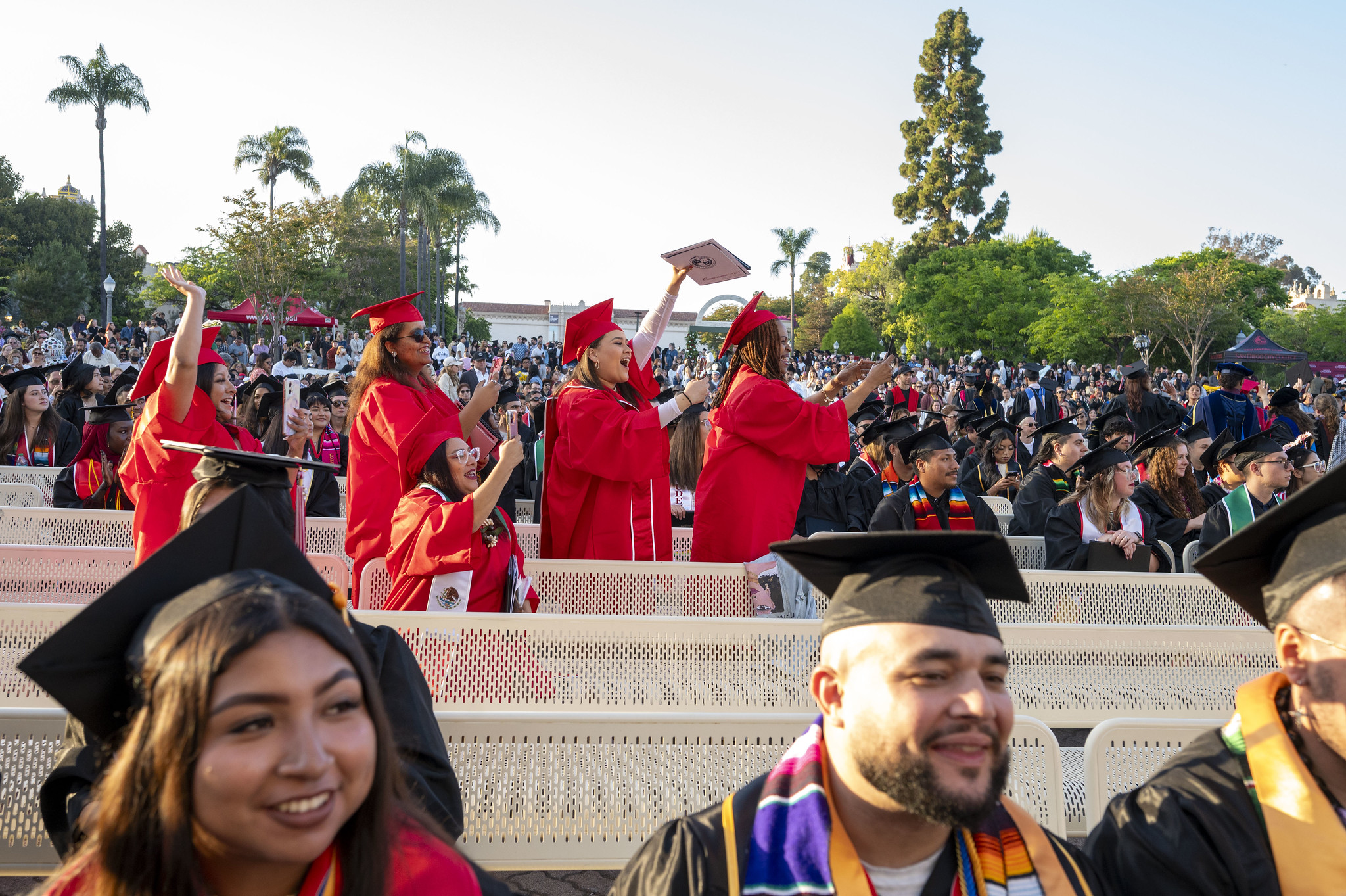 
Five cheering graduates return to their seats with their degrees.
