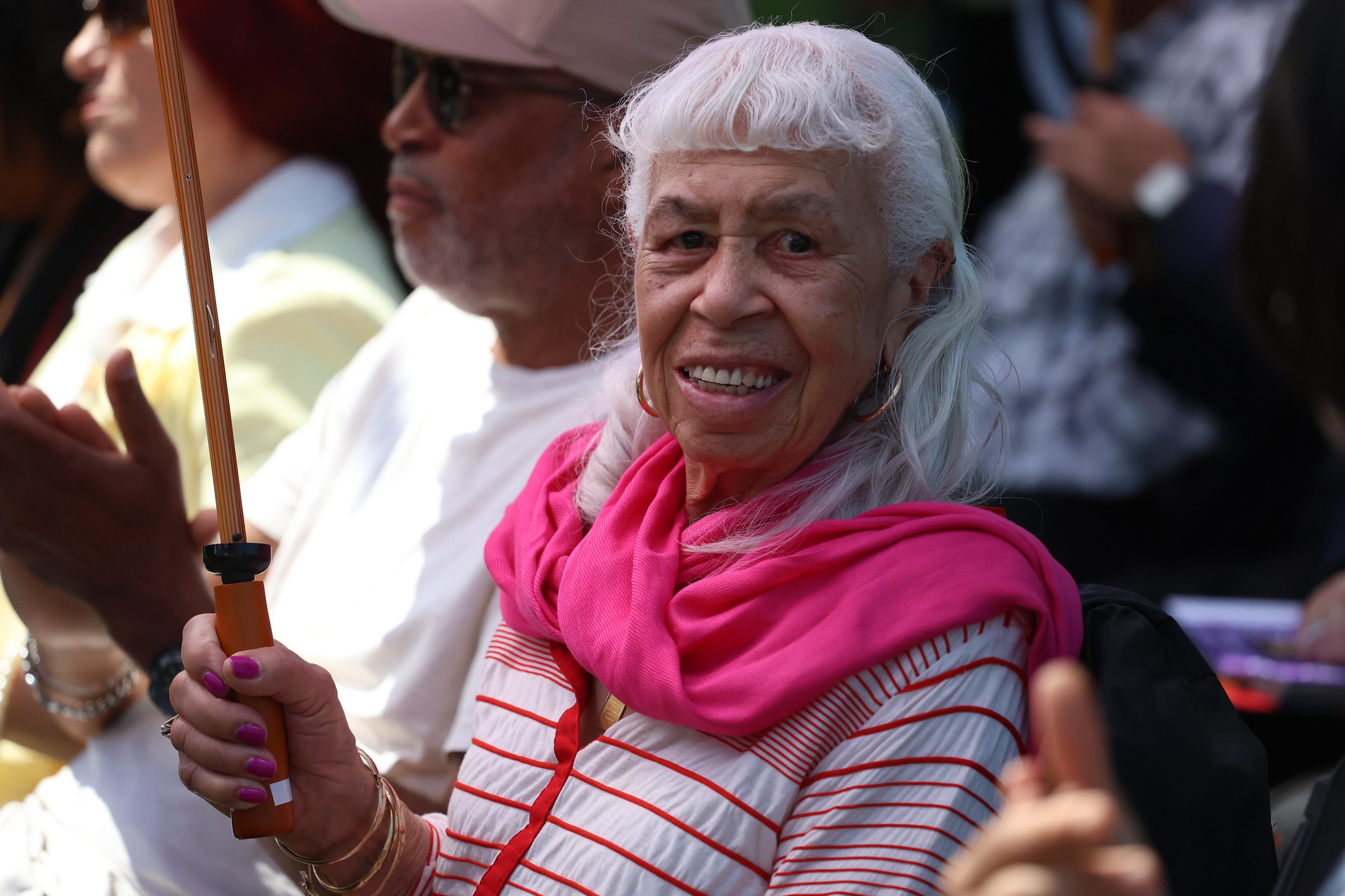 
A woman with a bright pink scarf smiling
