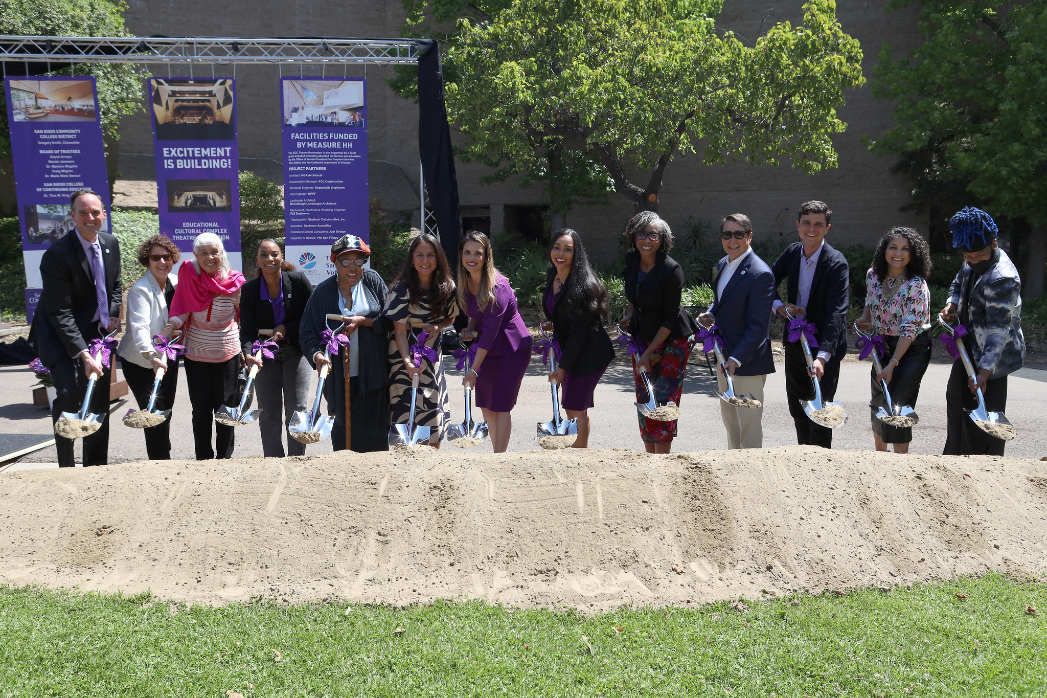 
Thirteen people shovel dirt at the groundbreaking.
