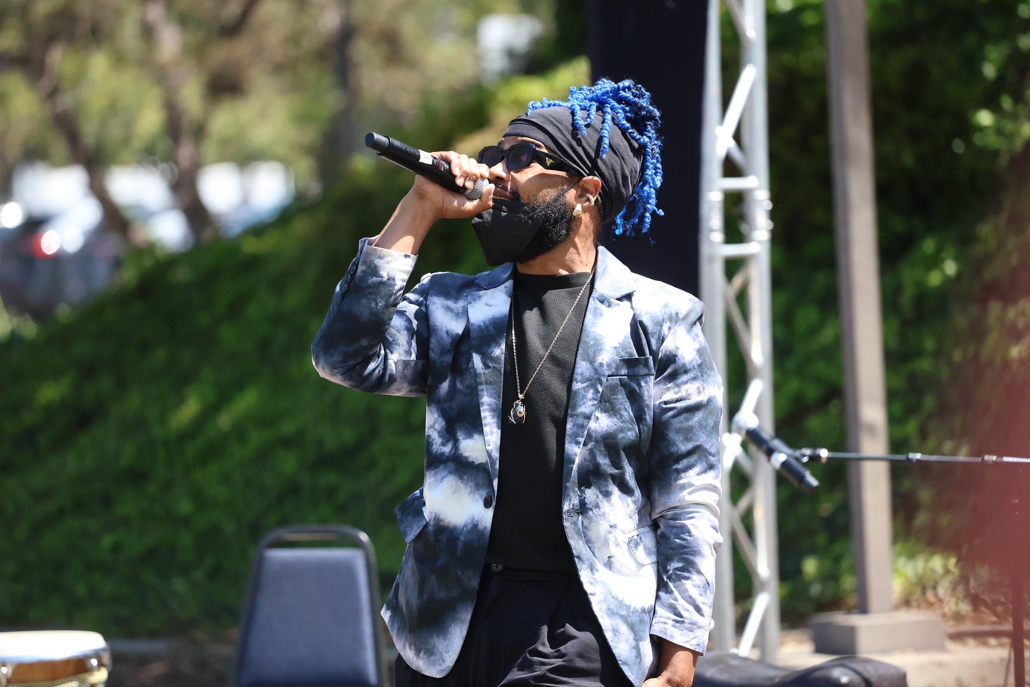 
A man in a blue and white tie dye jacket is singing.
