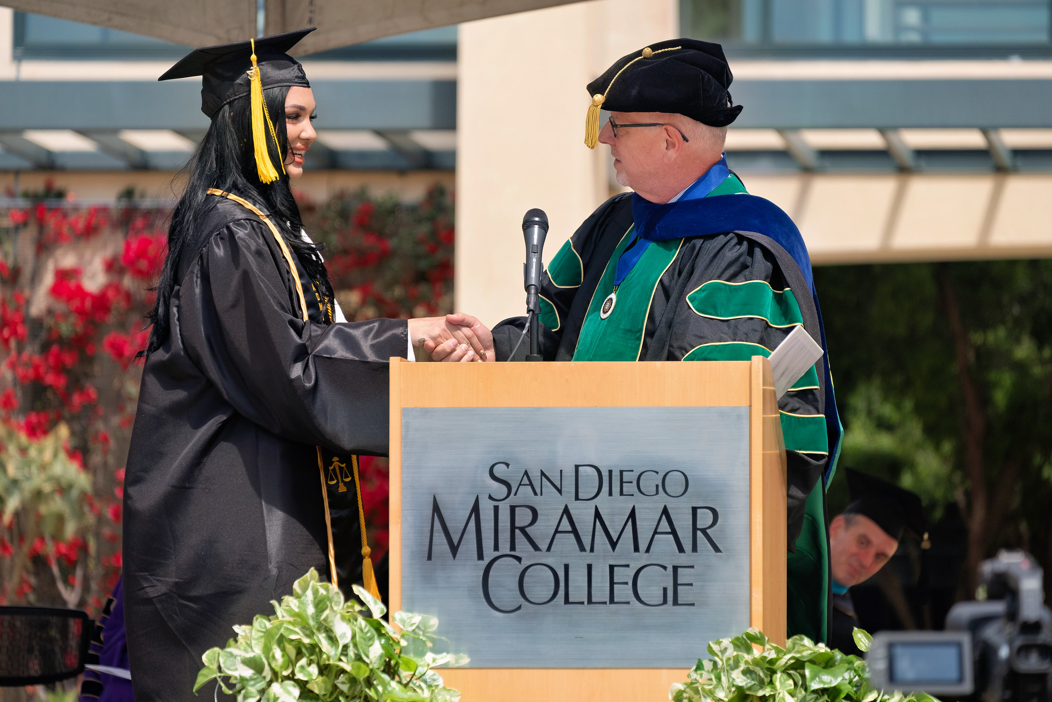 
The student speaker shakes Miramar President Wes Lundburg's hand at the podium.
