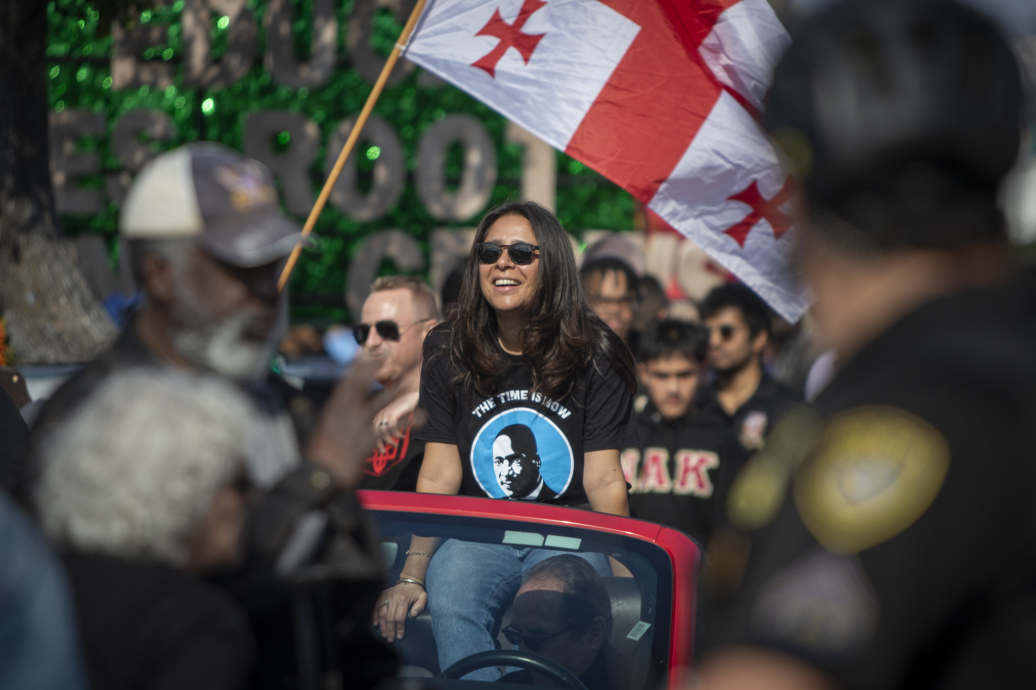 Trustee Geysil Arroyo sits in a red convertible that is driving in the parade.