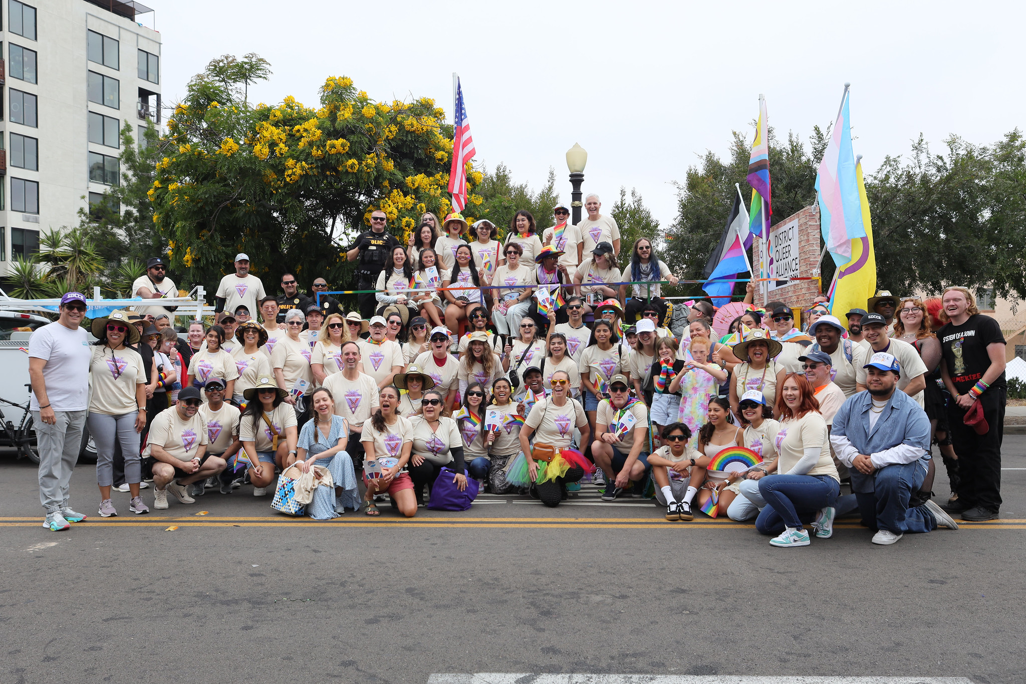 
About 50 people in matching Pride t-shirts take a group photo in front of the SDCCD Pride float.
